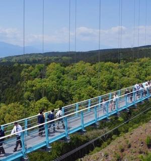 a group of people walking on a bridge over a mountain