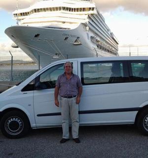 a man standing next to a white van in front of a cruise ship