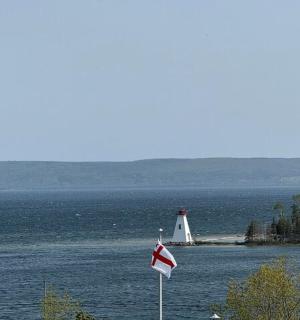 a lighthouse in the middle of the water with two flags