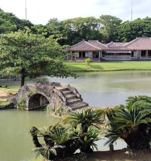 a bridge over a pond with a building in the background