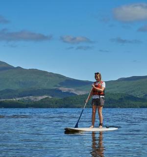 žena stojící na paddleboardu na jezeře