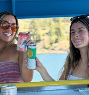 kaks naist istuvad laua taga ja hoiavad jooke käes