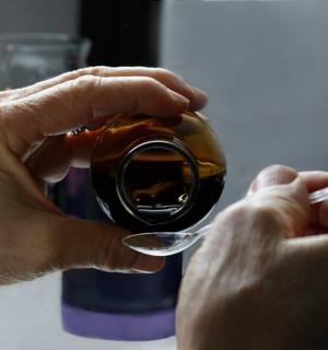 用勺子从玻璃杯中喝水的人