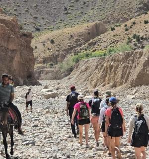 skupina lidí jezdících na koních po kamenité stezce
