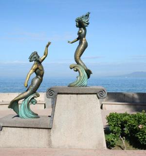 patung tiga ikan duyung di dinding berhampiran lautan