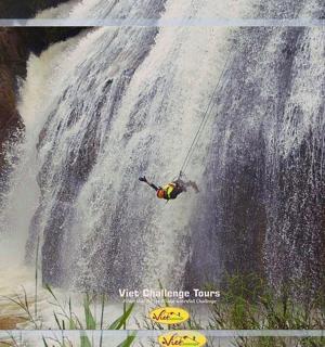 muž na laně visící z vodopádu