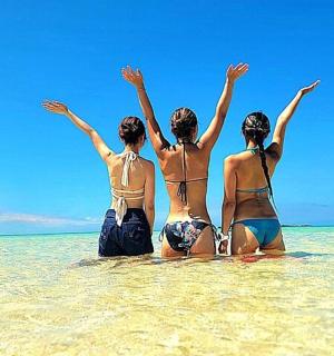 three women sitting in the water on the beach