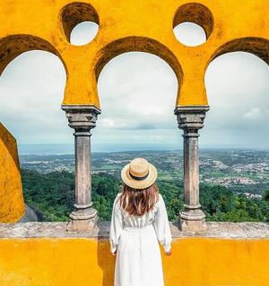 a woman in a hat looking out of a yellow building