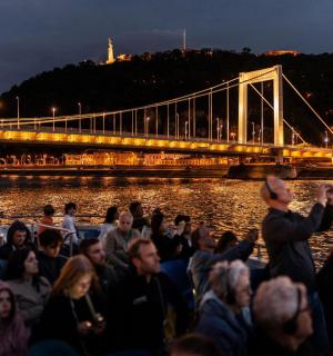 a crowd of people sitting next to a bridge