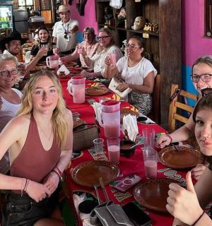 sekumpulan wanita duduk di meja makan kek