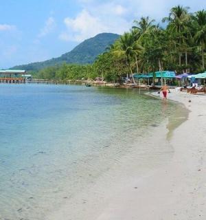 a woman walking on a beach with tables and umbrellas