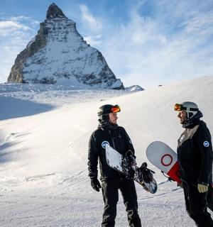 两个男人站在雪地里，手里拿着滑雪板