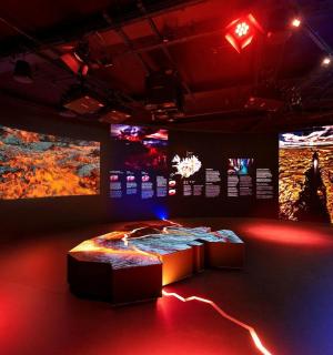 a room with a bed and two large televisions