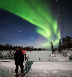 北极光下，一个人站在雪地里的滑雪板上
