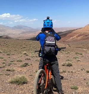 一名背着背包的男子骑着自行车站在沙漠中