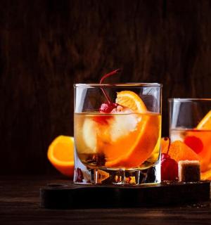 桌上有两杯鸡尾酒，配橙子和水果