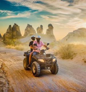 two people riding on a four wheeler on a dirt road