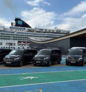 a group of cars parked in front of a cruise ship