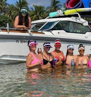 a group of women in the water in front of a boat