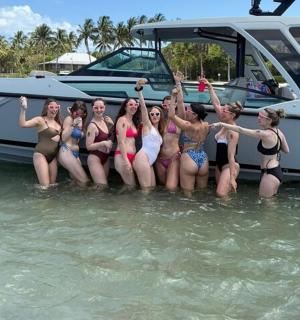 a group of women standing in the water next to a boat