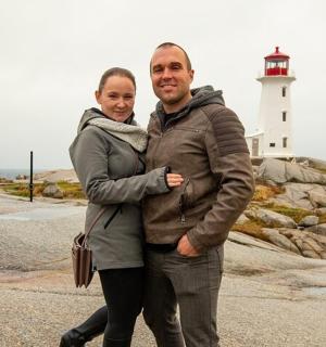 a man and woman standing in front of a lighthouse