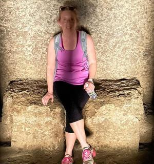 žena sedící na kamenné zdi a držící láhev s vodou