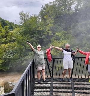three women standing on a bridge with their hands up