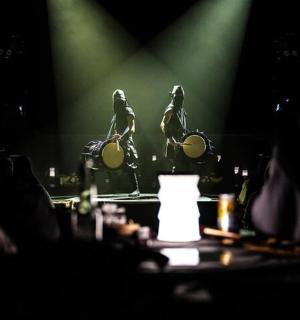 a group of people watching a stage with two birds on drums