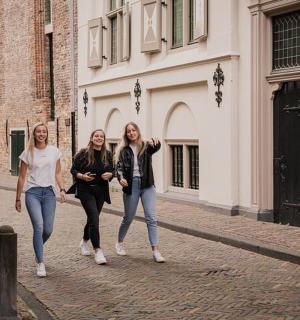 三个女人走在一栋建筑前的街道上