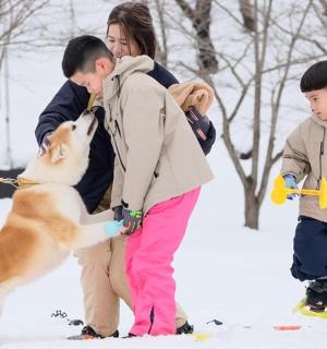 a woman and two children and a dog in the snow