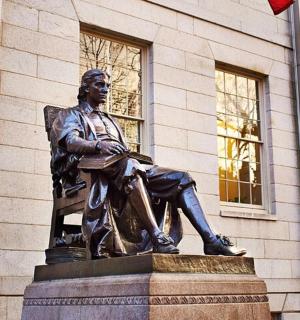 a statue of a man sitting in a chair in front of a building