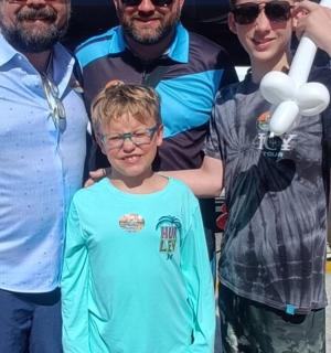 a group of people standing around a boy with balloons