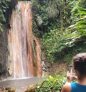 a woman taking a picture of a waterfall