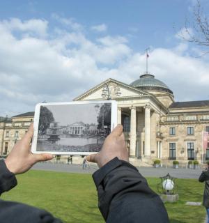 一名男子在建筑物前举着一张照片