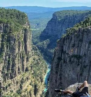 bir kanyona bakan bir uçurumun tepesinde yatan bir kişi