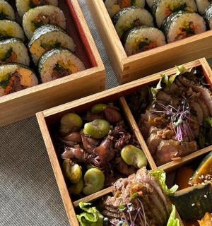 three wooden boxes filled with different types of sushi
