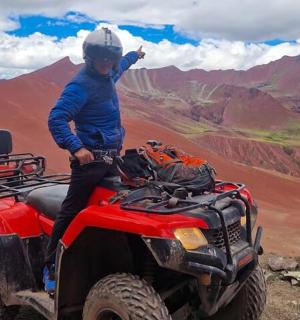 a man standing on a four wheeler on a mountain