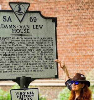 a woman in a hat standing next to a sign