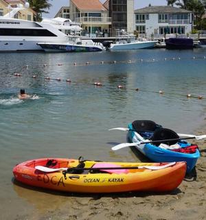 osoba plavající ve vodě vedle dvou lodí