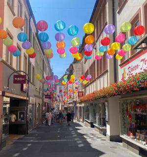 eine Straße mit bunten Luftballons, die von Gebäuden hängen