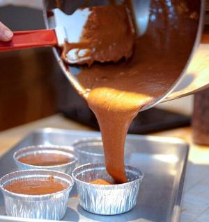 a person is pouring sauce into cups on a tray