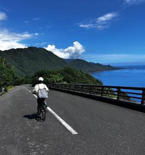 a person riding a bike on a road near the ocean