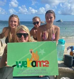 四个女孩坐在海滩上,手里拿着一块牌子