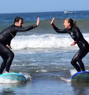 两个人穿着潜水服站在海里的冲浪板上