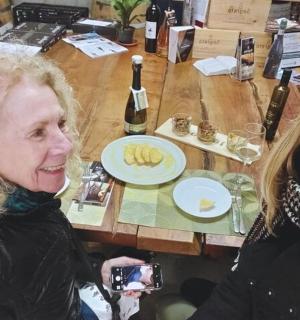 two women sitting at a table with wine bottles