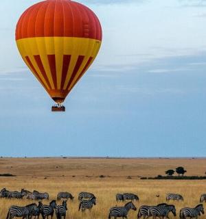 horkovzdušný balón letící nad stádem zeber