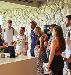 a group of people standing around a counter with a computer