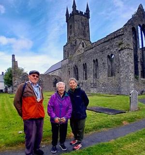 three people standing in front of an old church