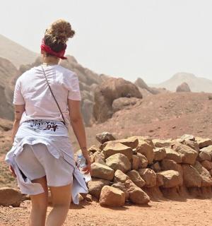 a woman in a white dress walking through the desert