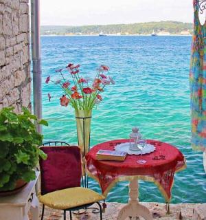 ein Tisch mit einer Vase mit Blumen neben dem Wasser